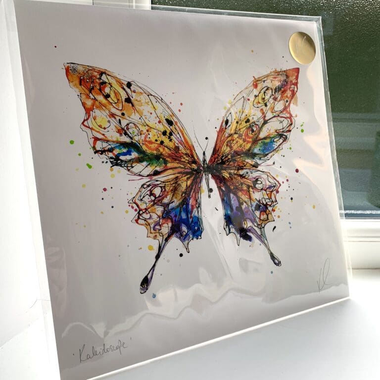 A print of Kaleidoscope by Kathryn Callaghan, which features a magnificent butterfly with wings of orange, blue, purple, and green. The 30cm print is presented flat in a clear cello bag with a golden KC sticker in the top right.