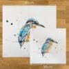 Two prints of Gaze by Kathryn Callaghan, a print of a perched kingfisher, to show the size difference between the 45cm print and the 30cm print.