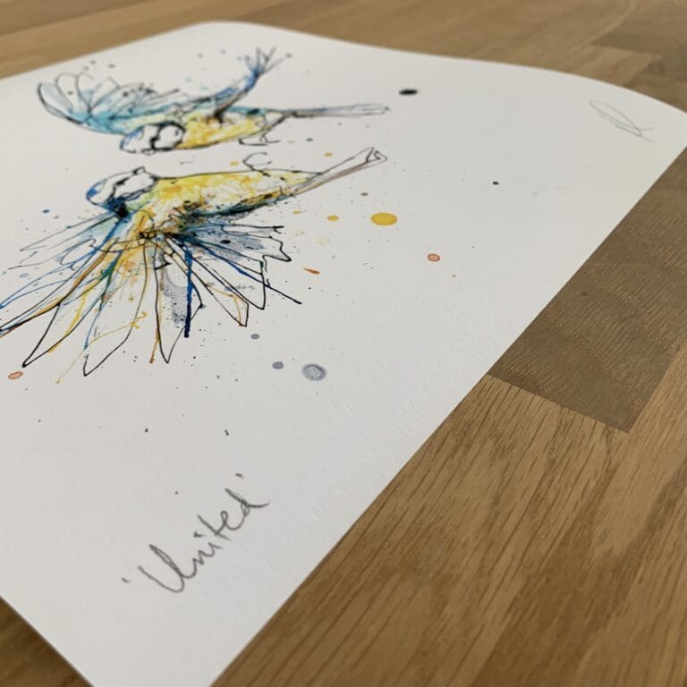 Photograph of United by Kathryn Callaghan, a print of two blue tits in mid flight, which shows the print's title handwritten in the bottom left corner and the artist's signature in the bottom right, with space between to add a custom personalisation.