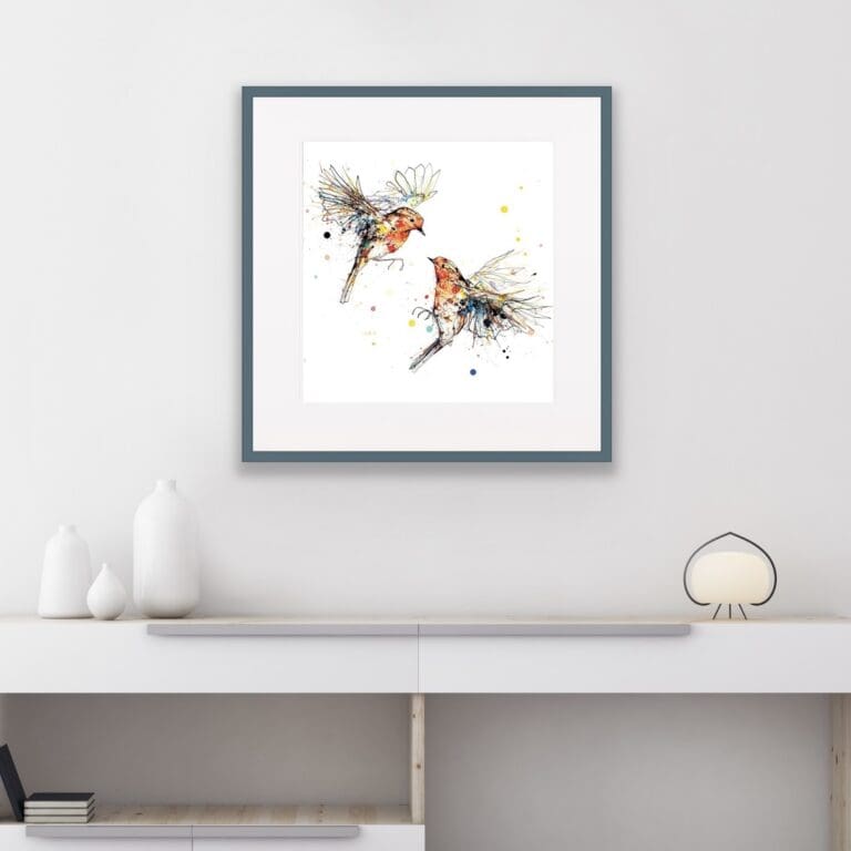 Two robins in flight print Showdown shown in dark grey frame in situ above a white sideboard