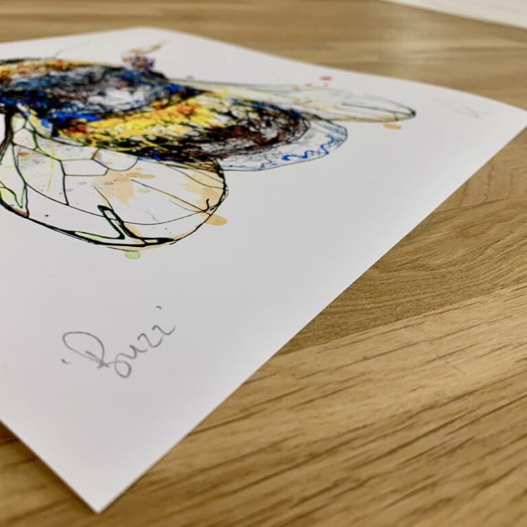 Photograph of Buzz by Kathryn Callaghan, a print of a bumblebee, which shows the print's title handwritten in the bottom left corner and the artist's signature in the bottom right, with space between to add a custom personalisation.