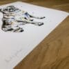 Photograph of Anticipation by Kathryn Callaghan, a print of a sitting pug, which shows the print's title handwritten in the bottom left corner and the artist's signature in the bottom right, with space between to add a custom personalisation.