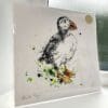 A print of Atlantic puffin, which features a puffin sitting on a branch by Kathryn Callaghan. The 30cm print is presented flat in a clear cello bag with a golden KC sticker in the top right.