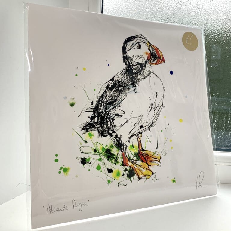 A print of Atlantic puffin, which features a puffin sitting on a branch by Kathryn Callaghan. The 30cm print is presented flat in a clear cello bag with a golden KC sticker in the top right.