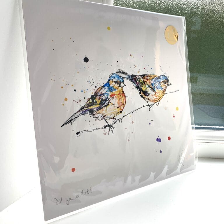 A print of Did You See That? which features two chaffinches sitting on a branch by Kathryn Callaghan. The 30cm print is presented flat in a clear cello bag with a golden KC sticker in the top right.