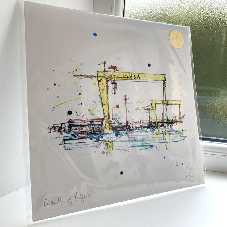 A print of Giants of Belfast by Kathryn Callaghan, featuring the Harland & Wolff cranes. The 30cm print is presented flat in a clear cello bag with a golden KC sticker in the top right.