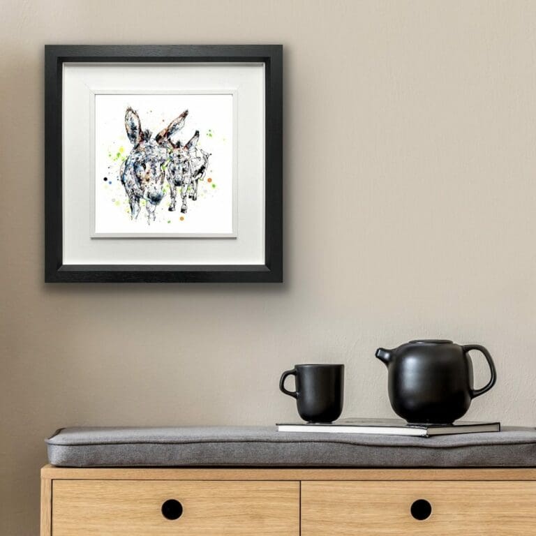 Companions Donkeys print shown in deluxe black frame in situ above sideboard with teakettle and cup