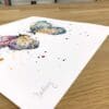 Photograph of Destiny, a print of two colourful butterflies by Kathryn Callaghan, which shows the print's title handwritten in the bottom left corner and the artist's signature in the bottom right, with space between to add a custom personalisation.