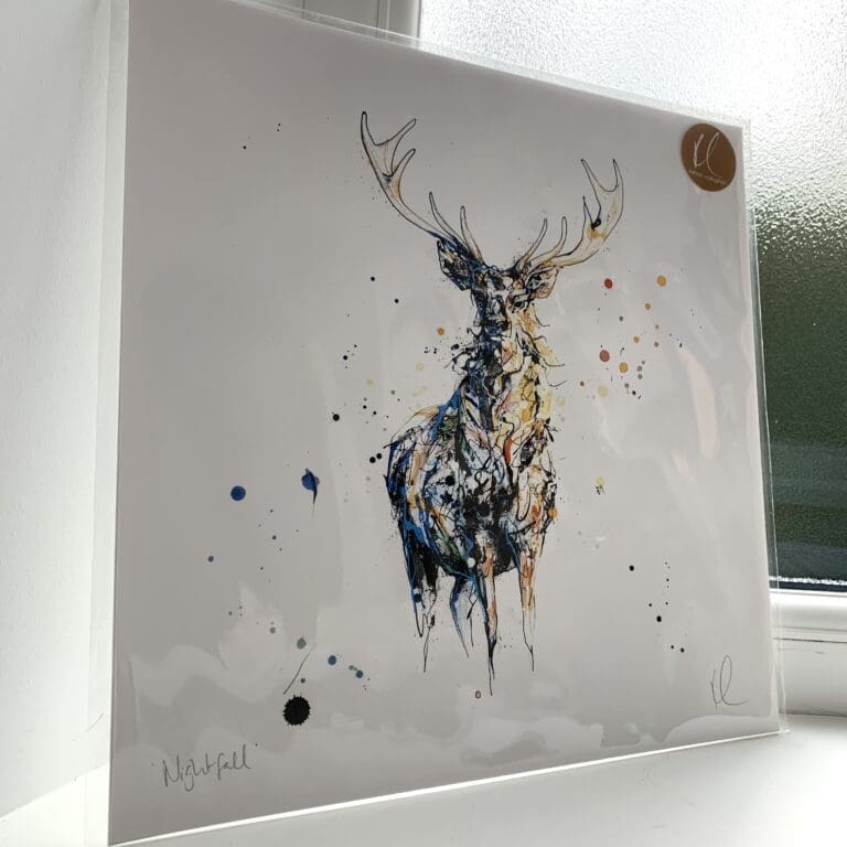 A print of Nightfall by Kathryn Callaghan, which features a stag standing gazing at the viewer, lit in tones of dark blue and gold. The 30cm print is presented flat in a clear cello bag with a golden KC sticker in the top right.