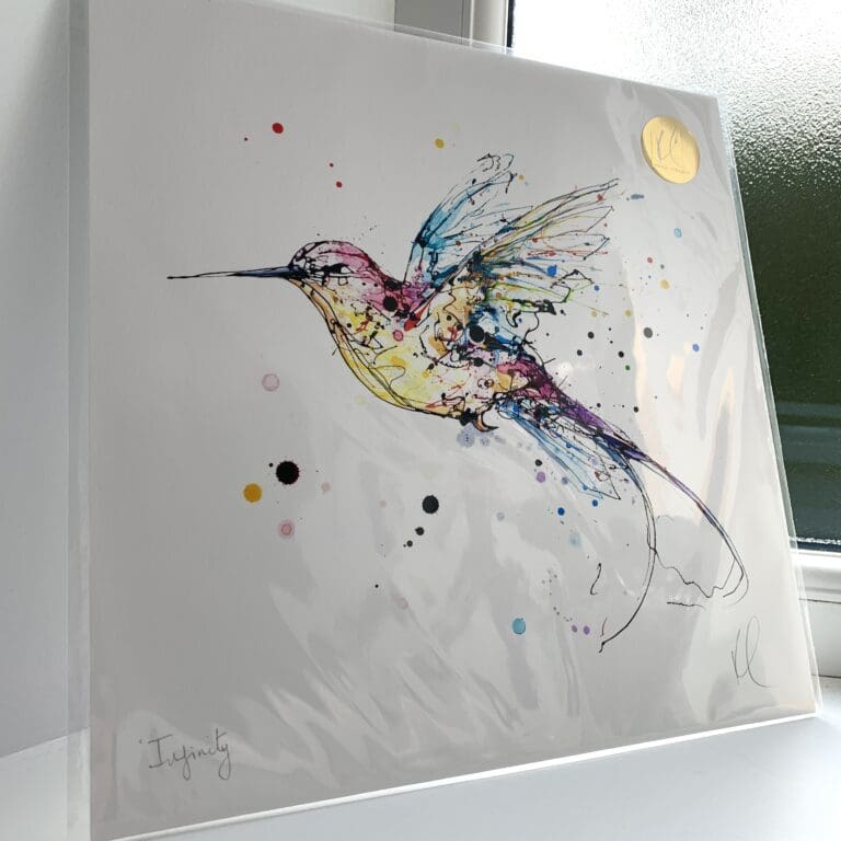 A print of Infinity by Kathryn Callaghan, which features a pink, yellow and blue hummingbird flying from right to left. The 30cm print is presented flat in a clear cello bag with a golden KC sticker in the top right.