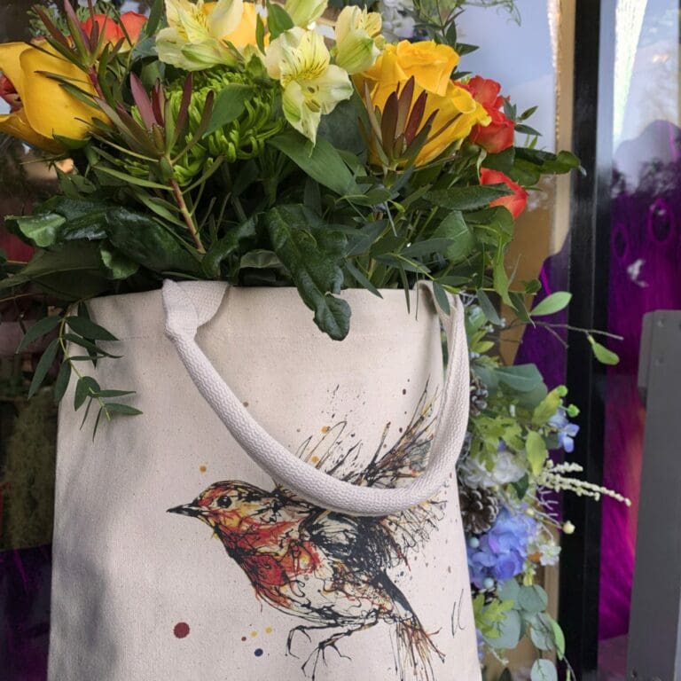 Canvas bucket tote bag featuring robin print filled with orange and yellow flowers and green foliage