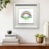 Under the Same Rainbow NHS Print shown in Deluxe White Frame in Situ above sideboard with books and plant