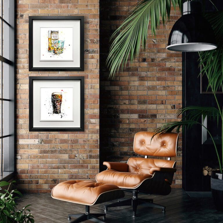 Two prints are shown framed in situ in a room with exposed red brick, a smart leather recliner and a palm plant. The prints are A Wee Night Cap, which shows a glass of whiskey and a bottle, and The Black stuff, which shows a pint of Guinness. They are both in Deluxe Black Frames.