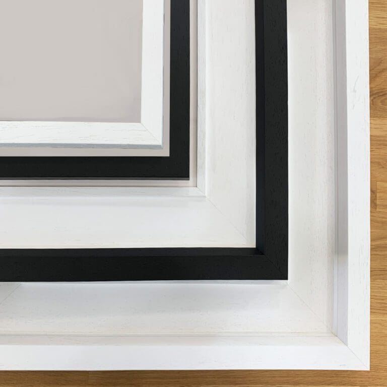 Corners of white and black wooden frames against a natural wood grain.