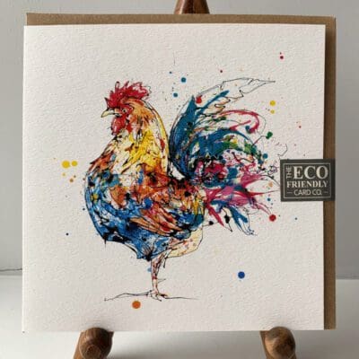 Greetings card featuring a poured painting of a colourful cockerel named Clarence by Kathryn Callaghan, and comes with a brown recycled envelope. A sticker on the card reads "The Eco Friendly Card Company".