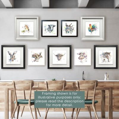 Nine framed prints in alternating white and black frames are shown in a dining room on a grey wall above a pine table and chairs. The prints are Little Guy featuring a mouse, Pastures New featuring a dairy cow, Companions featuring two donkeys, Clarence featuring a cockerel, Hartley featuring a hare's face, Like The Wind featuring a running hare, Harris featuring a highland cow, Truffles featuring a pig, and Hudson featuring a horse. Text reads "Framing shown is for illustrative purposes only; please read the description for more detail."