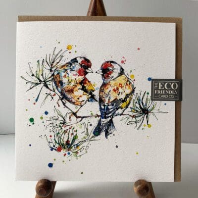 Greetings card featuring a poured painting of a pair of goldfinches by Kathryn Callaghan. The gold finches are orange and red and sitting on a fir branch. A sticker on the card reads "The Eco Friendly Card Company".