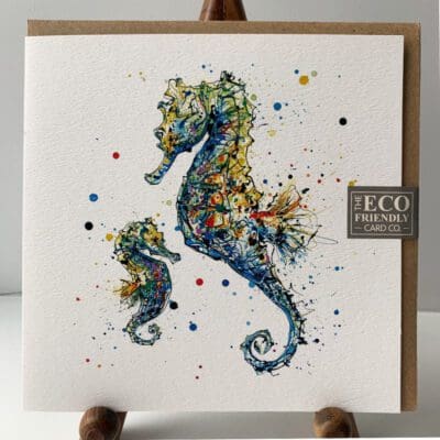 Greetings card featuring a poured painting of an adult and baby seahorse by Kathryn Callaghan. A sticker on the card reads "The Eco Friendly Card Company".