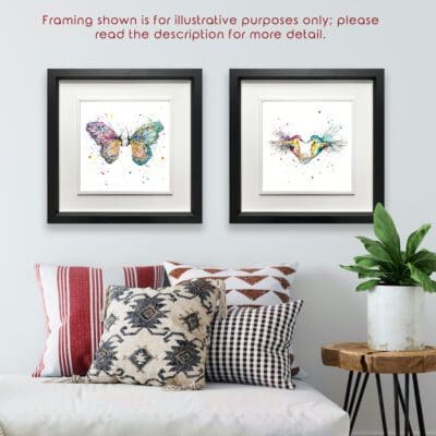 Two prints are shown in Deluxe Black Frames in situ above red and black pillows and a plant. The prints are Destiny, which depicts two butterflies facing each other, and Forever, which depicts two hummingbirds flying in the shape of a heart. Text reads "framing shown is for illustrative purposes only; please read the description for more detail".