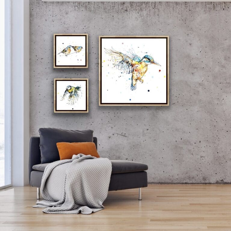 The Golden Hour kingfisher in flight print, Did You See That chaffinches print, and Coat of Colour blue tit print, all by Kathryn Callaghan shown in situ in a concrete-walled room.