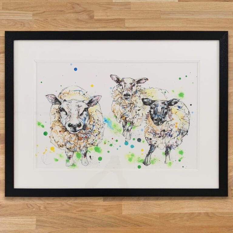 All Ears Original Sheep Painting by Kathryn Callaghan, framed in a classic black frame with double white mount set on a wooden worktop.