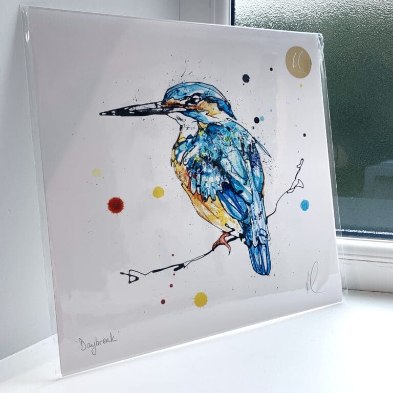 A print of Daybreak by Kathryn Callaghan, which features a bright kingfisher posed on a branch. The 30cm print is presented flat in a clear cello bag with a golden KC sticker in the top right.