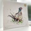 A print of Attention by Kathryn Callaghan, which features a charismatic pheasant looking back at the viewer. The 30cm print is presented flat in a clear cello bag with a golden KC sticker in the top right.