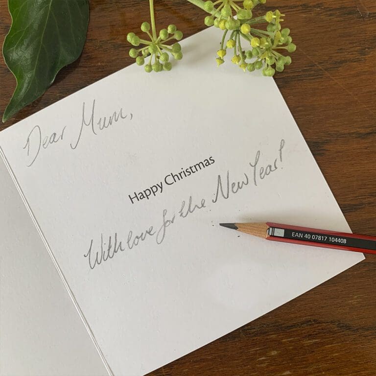 A hand written message inside a Christmas Card reading "Dear Mum, With love for the New Year!" alongside a printed message of "Happy Christmas".