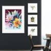 As Night Falls, a print of tulips on a mauve background by Kathryn Callaghan, is shown alongside three prints of a kingfisher, bumblebee, and blue tit in a dark well lit office.