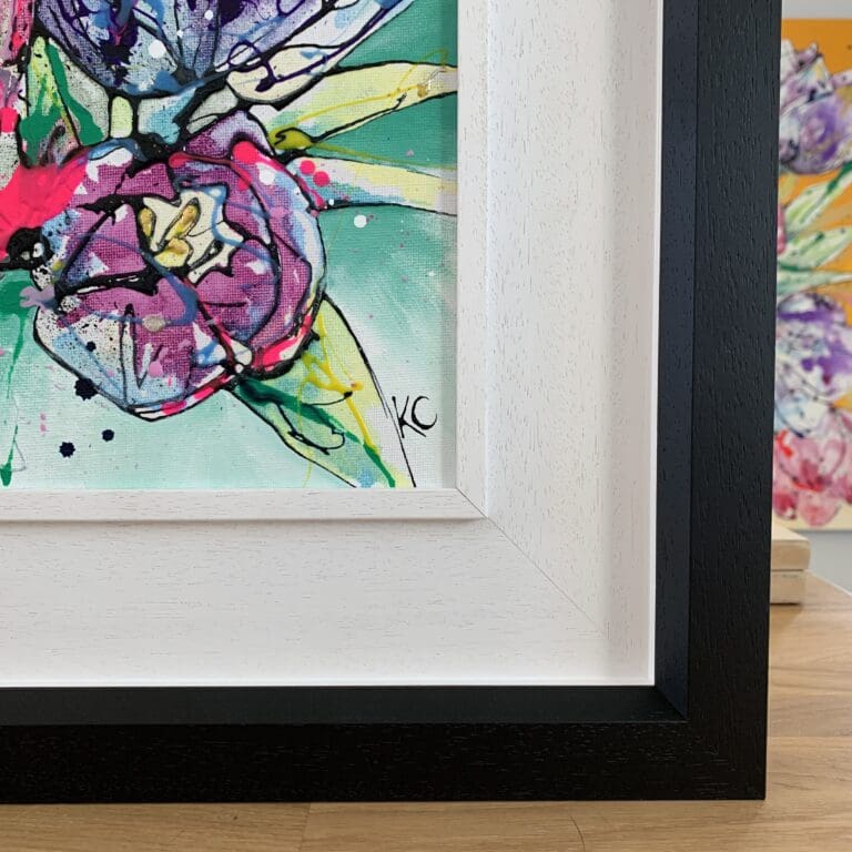 Close up photograph depicting the black ink signature and wooden two part black and white frame of Peace, an original floral painting by Kathryn Callaghan.