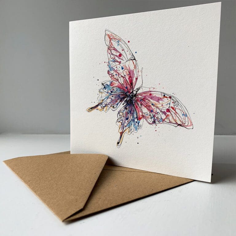 A greetings card by Kathryn Callaghan featuring Flutterfly, a print of a pink and blue butterfly, sitting alongside its brown paper envelope.