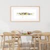 Essence of the Mournes, a print by Kathryn Callaghan, shown framed in a light wood frame in an airy dining room with matching light wood furniture.