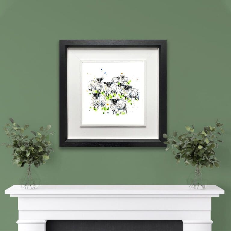 A print of a flock of sheep named Baa by Kathryn Callaghan, shown in a deluxe black frame in situ on a green wall above a white mantlepiece with eucalyptus plants.