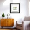 A print by Kathryn Callaghan shown in situ. The print, titled Belfast Docks, shows the Harland & Wolff cranes looming over the shipyard, and is shown framed in a deluxe two part black and white frame in a well lit living room.