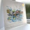 A print of Ha'penny Bridge, Dublin by Kathryn Callaghan, which features the eponymous iron bridge stretching from the bank of the Liffey in Dublin City Centre. The 30cm print is presented flat in a clear cello bag with a golden KC sticker in the top right.