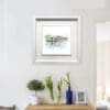 A print of Ha'penny Bridge, Dublin by Kathryn Callaghan, displayed in a deluxe white frame in situ in an airy home above a sideboard with plants.