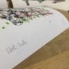 Photograph of Well Hello, a print of a herd of cows by Kathryn Callaghan, which shows the print's title handwritten in the bottom left corner and the artist's signature in the bottom right, with space between to add a custom personalisation.