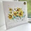 A print of Happy Days by Kathryn Callaghan, which features a vivid spray of daffodils. The 30cm print is presented flat in a clear cello bag with a golden KC sticker in the top right.