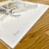 Photograph of Hover by Kathryn Callaghan, a print of a barn owl in flight, which shows the print's title handwritten in the bottom left corner and the artist's signature in the bottom right, with space between to add a custom personalisation.