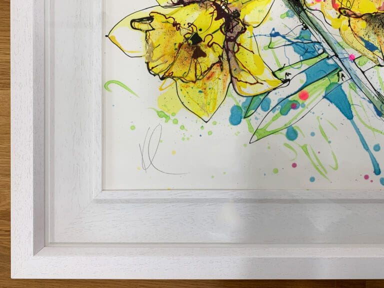 A close up photograph of Happy Days, an original painting of daffodils by Kathryn Callaghan. This close up shows the deluxe white wooden frame and the artist's KC signature.