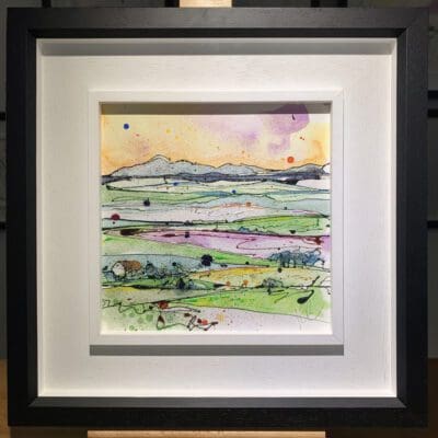 An original painting named Across the Drumlins by Kathryn Callaghan, featuring a rolling landscape inspired by County Down, Northern Ireland. The painting is framed in a two part white and black frame.