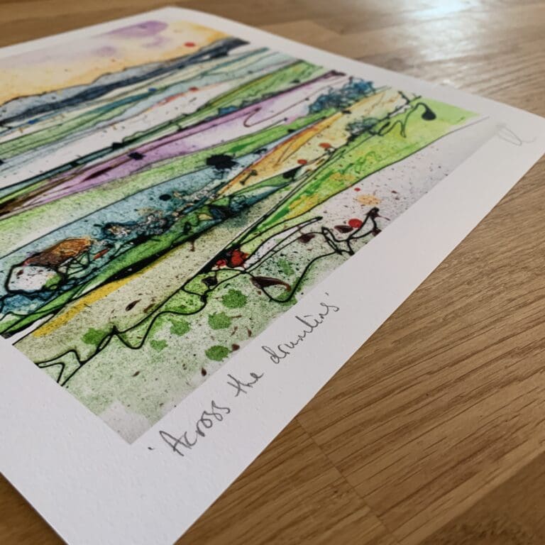 Photograph of Across the Drumlins by Kathryn Callaghan, which shows the print's title handwritten in the bottom left corner and the artist's signature in the bottom right, with space between to add a custom personalisation.