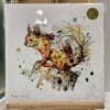 A print of Happy Go Lucky by Kathryn Callaghan, which features a red squirrel perched on a stump. The 30cm print is presented flat in a clear cello bag with a golden KC sticker in the top right.