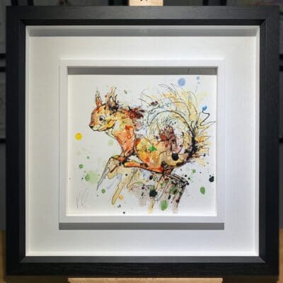 An original painting named Happy Go Lucky by Kathryn Callaghan, featuring a vivd red squirrel perched on a stump. The painting is framed in a two part white and black frame.