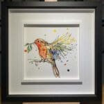 An original painting named I'm Home by Kathryn Callaghan, featuring a robin in flight with a sprig of mistletoe in its beak. The painting is framed in a two part white and black frame.