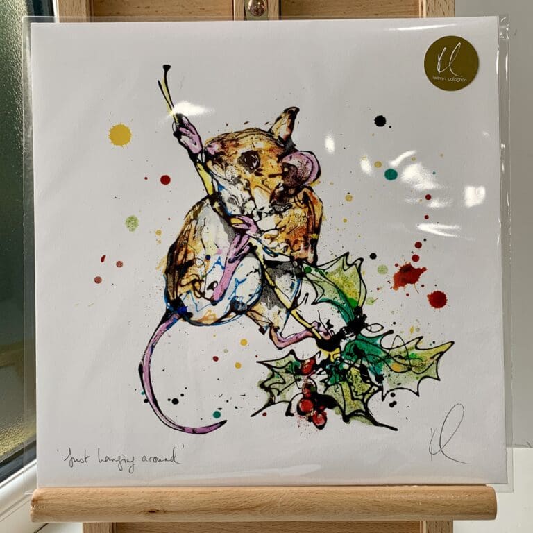 A print of Just Hanging Around by Kathryn Callaghan, which features a harvest mouse clambering up a holly stick. The 30cm print is presented flat in a clear cello bag with a golden KC sticker in the top right.