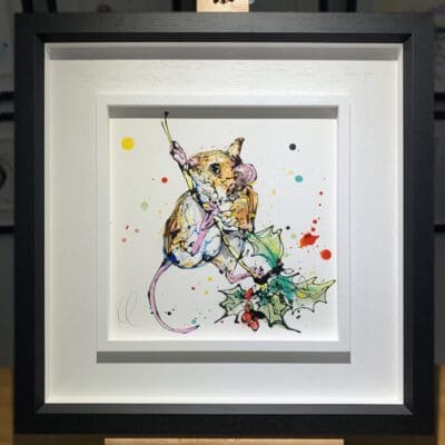 An original painting named Just Hanging Around by Kathryn Callaghan, featuring a harvest mouse curled around a sprig of holly. The painting is framed in a two part white and black frame.