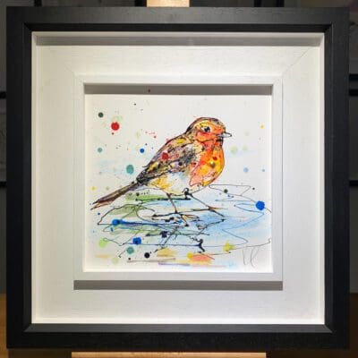 An original painting named Reflect by Kathryn Callaghan, featuring a robin standing in a blue puddle. The painting is framed in a two part white and black frame.