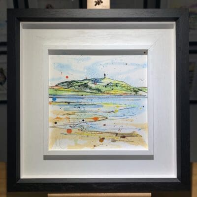 An original painting named Scrabo from the Lough by Kathryn Callaghan, featuring a view of Scrabo Tower from Strangford Lough in Northern Ireland, with sailboats on the water. The painting is framed in a two part white and black frame.