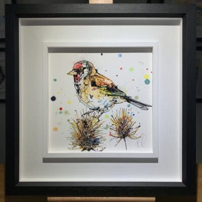 An original painting named Sundown by Kathryn Callaghan, featuring a goldfinch perched on a thistle. The painting is framed in a two part white and black frame.